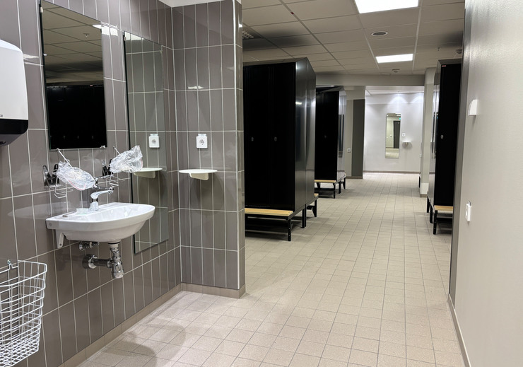 Del av omkl&auml;dningsrum f&ouml;r personal med handfat, spegel och svarta sk&aring;p.