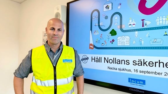 En man i Locumväst står framför en stor skärm.