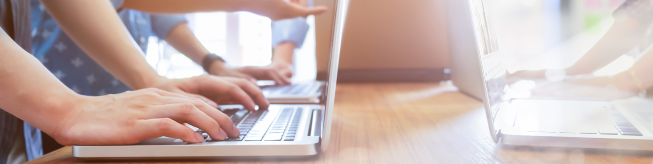 En grupp människor som sitter vid ett bord med bärbara datorer.