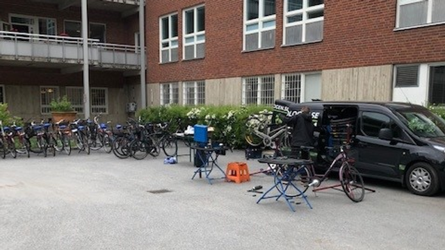 En parkeringsplats med ett gäng cyklar parkerade framför en byggnad.