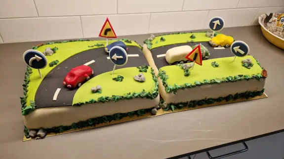 Två tårtor med bilar på på en bänk.