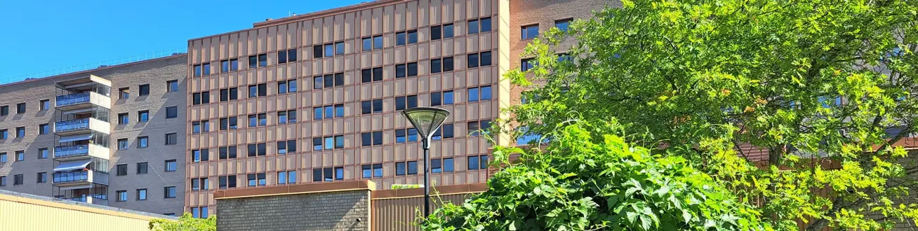 En stor byggnad med många fönster intill en trädgård.