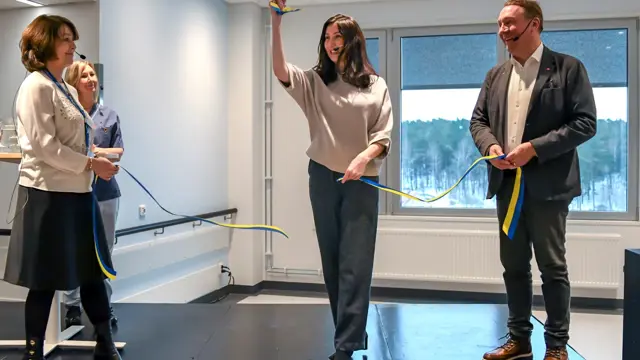 En grupp människor som klipper ett band på en scen.