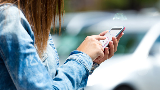 En kvinna ska starta parkering på sin mobiltelefon.
