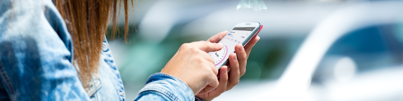 En kvinna ska starta parkering på sin mobiltelefon.