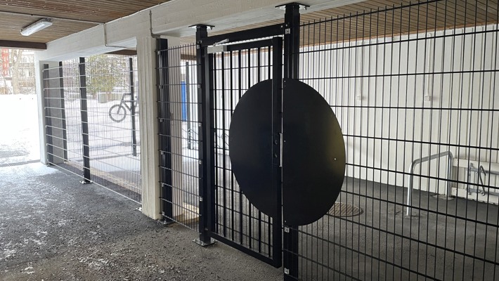 Inh&auml;gnad cykelparkering med vit cykelsymbol p&aring; v&auml;ggens galler.