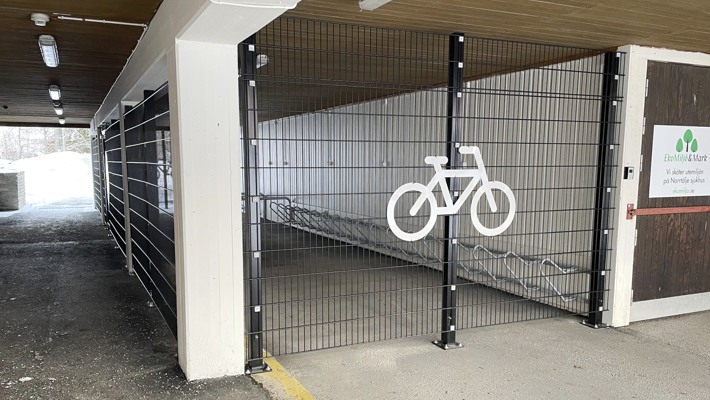 Inh&auml;gnad cykelparkering med vit cykelsymbol p&aring; v&auml;ggens galler.