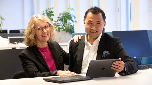 Två av Locums chefer står vid ett bord med en bärbar dator.