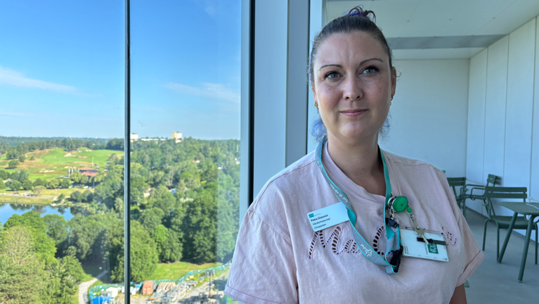 Kvinna i ljus t-shirt står på en balkong med utsikt över Edsviken.