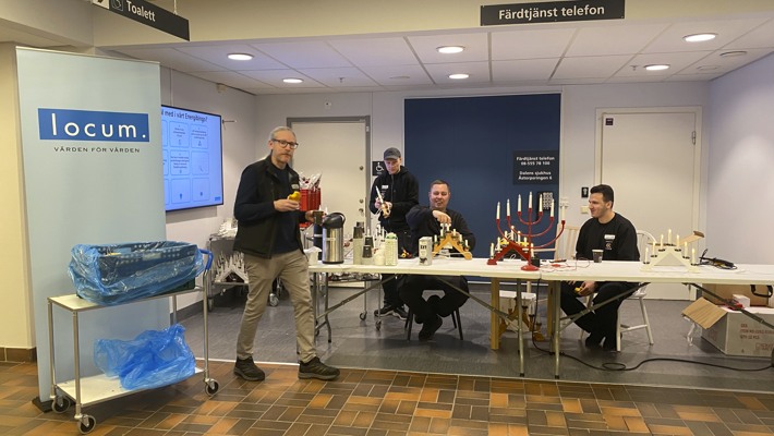 En grupp m&auml;nniskor som sitter runt ett bord och byter ut ljus i elljusstakar.