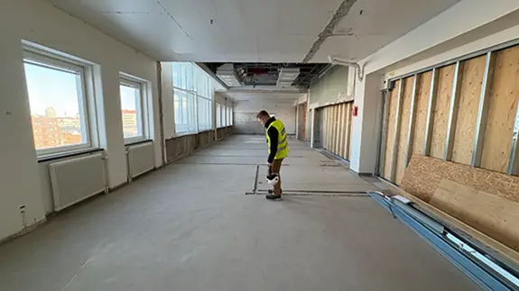 En bild på de tidigare operationssalarna på Södersjukhuset. I mitten står en projektledare och inspekterar golvet.