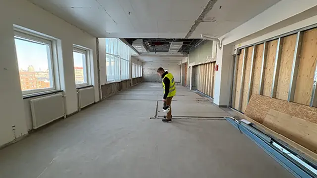 En bild på de tidigare operationssalarna på Södersjukhuset. I mitten står en projektledare och inspekterar golvet.