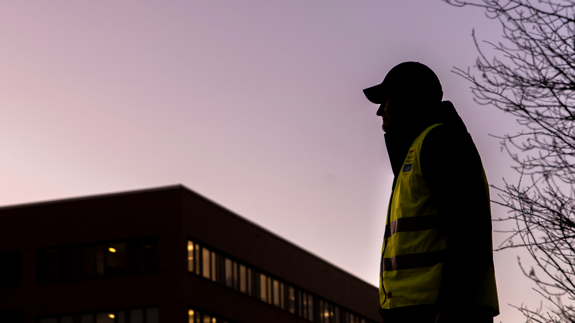 En locum personal
 som står framför en hög byggnad. Det är skymning.