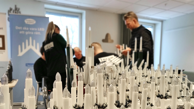 Flera ljusstakar står uppradade. Fyra personer i bakgrunden.