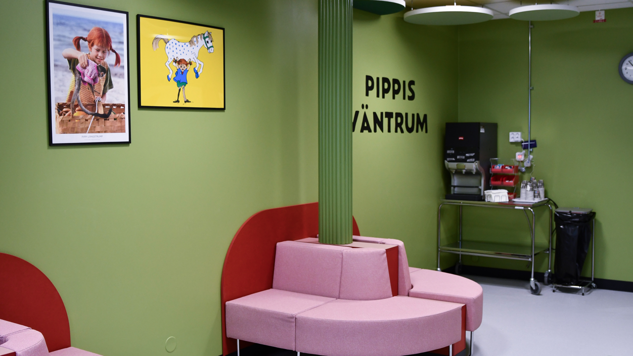 Ett gr&ouml;nt rum med rosa stolar och tavlor p&aring; v&auml;ggen.