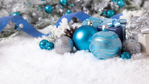 En blå och silverfärgad julprydnad i snön.