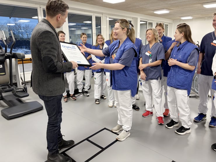 Locums energicontroller l&auml;mnar &ouml;ver diplom f&ouml;r energibingo till medarbetare p&aring; fysipterapin vid Danderyds sjukhus.