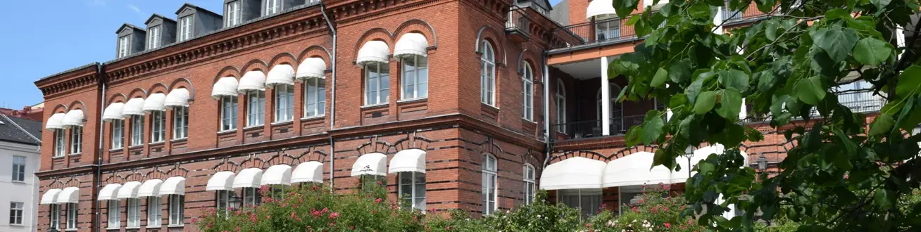 En stor röd tegelbyggnad som ligger på ett grönskande fält.