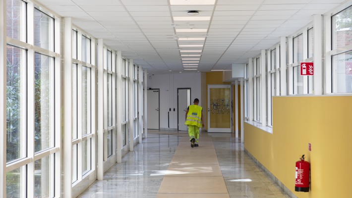 Person med varselv&auml;st g&aring;r i korridor inomhus p&aring; Solna sjukhusomr&aring;de.