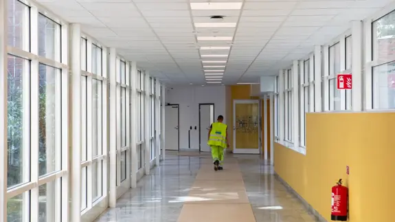 En person som går längs en lång korridor med många fönster.