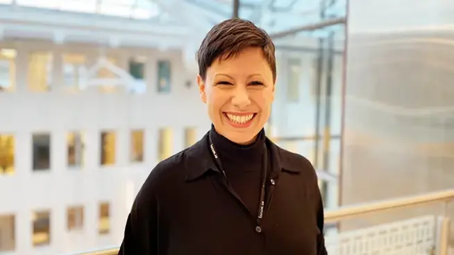 Nadia har en svart tröja på sig och ler mot kameran. 