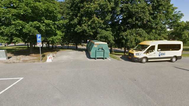 En sk&aring;pbil som stod parkerad p&aring; en parkeringsplats bredvid en container.