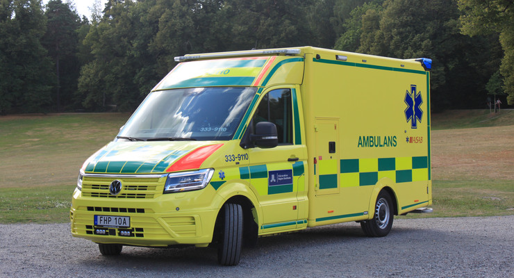 Ambulans parkerad på grusplan.