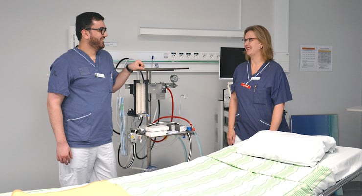 En man och en kvinna står vid en sjukhussäng.