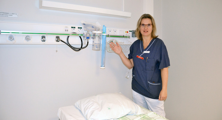 En kvinnlig läkare står bredvid en sjukhussäng.