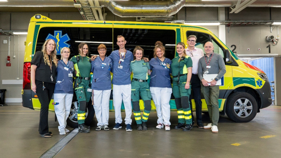 Personal från Södersjukhuset och Ambulanssjukvården står framför en ambulans.