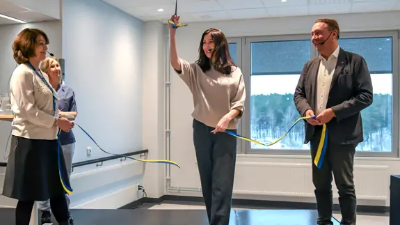 En grupp människor som klipper ett band på en scen.