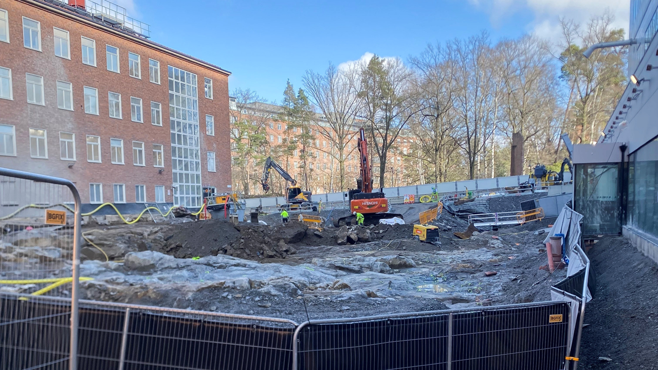 En byggarbetsplats med ett staket och en byggnad i bakgrunden.