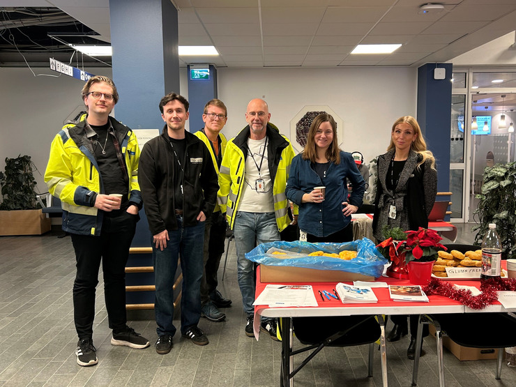 Sex Locummedarbetare st&aring;r vid ett bord med informationsmaterial.