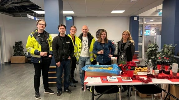 Sex Locummedarbetare står vid ett bord med informationsmaterial.