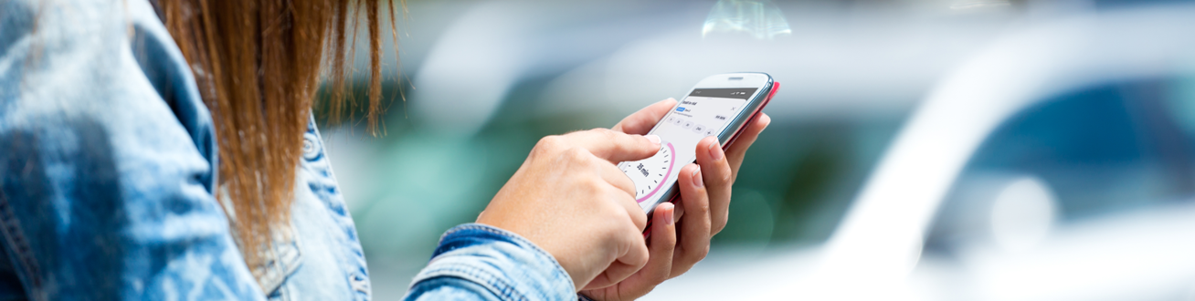 En kvinna ska starta parkering på sin mobiltelefon.