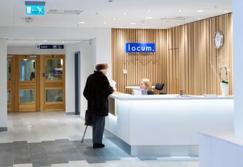 Vit receptionsdisk med besökare som pratar med receptionist.