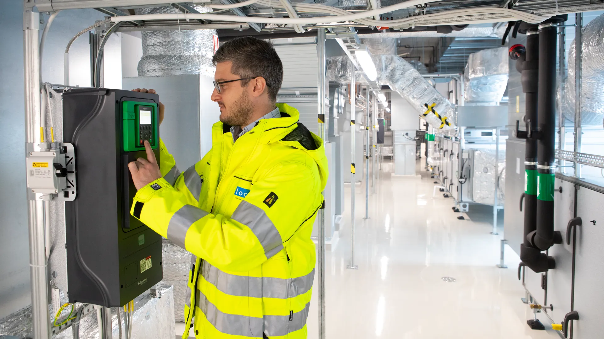 Medarbetare i gul varseljacka i ett fl&auml;ktrum i fastighet.