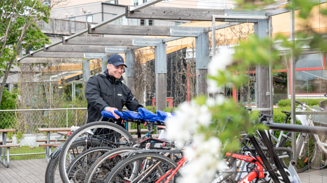 En man som står bredvid ett gäng cyklar.