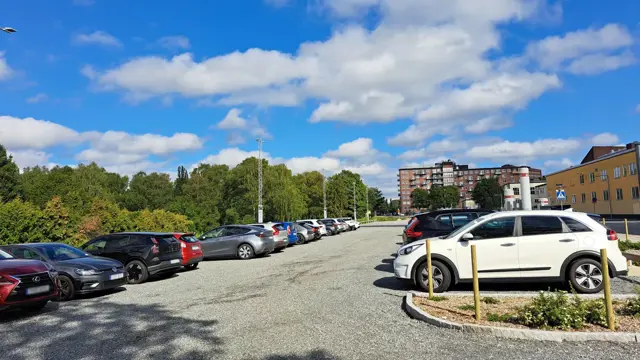 Grusad parkeringsyta med parkerade bilar på. 