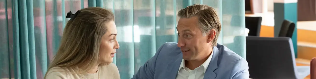 Manlig och kvinnlig medarbetare tittar på varandra och pratar.