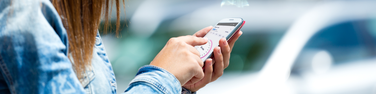 En kvinna ska starta parkering på sin mobiltelefon.