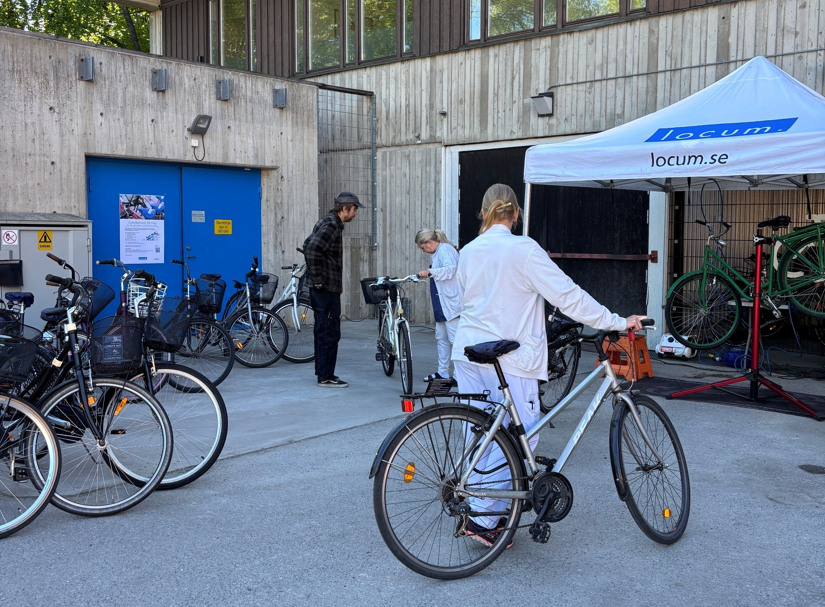 Kvinna med vita kläder leder cykel under cykelservice.