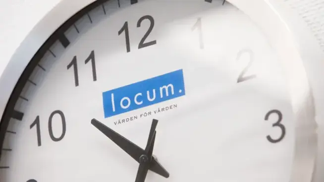 Väggklocka med Locums logotyp på.