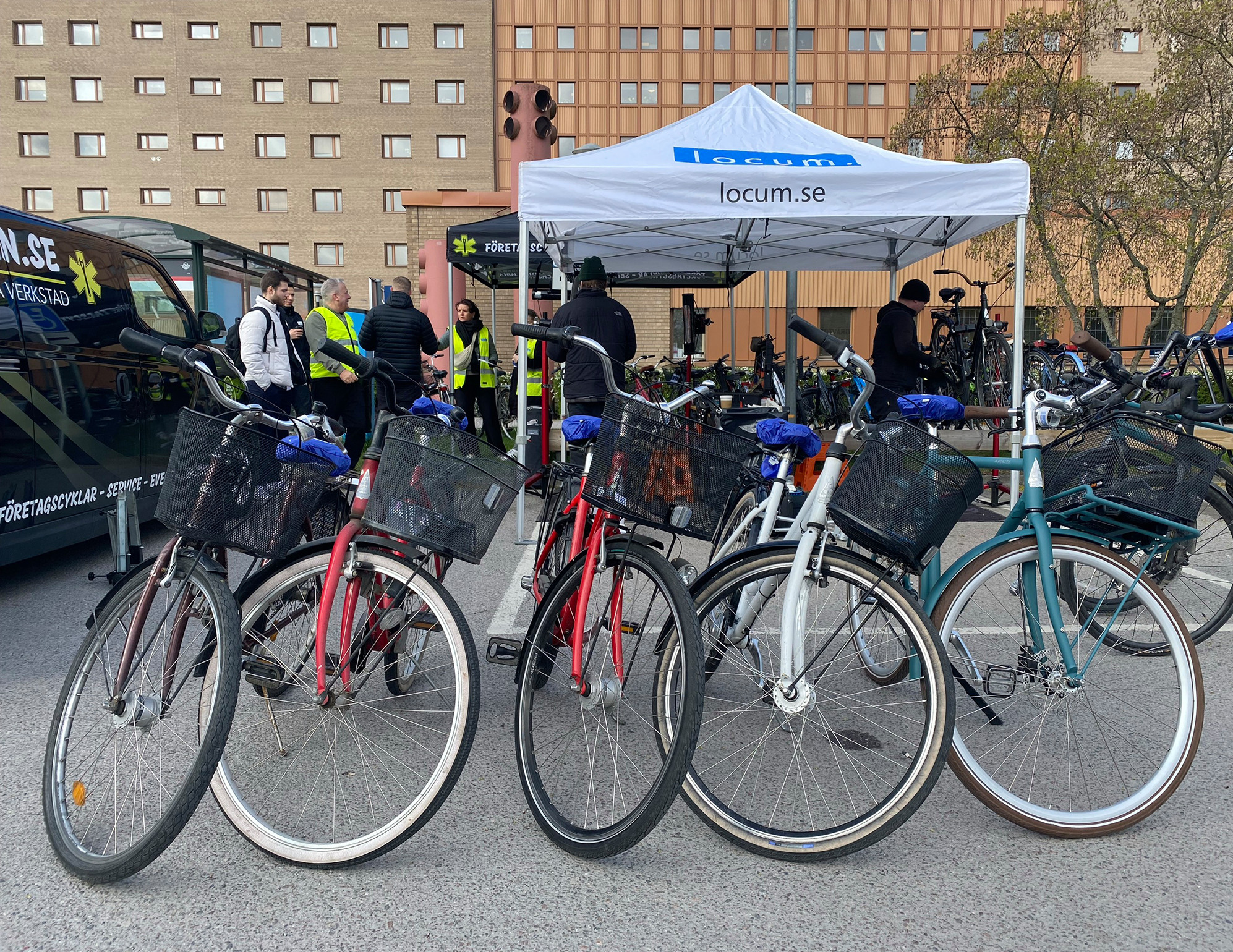 Cyklar står uppställda på rad. Människor står i bakgrunden.