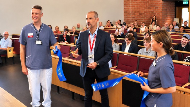 Sjukhusdirektörn klipper band med två medarbetare från verksamheten.