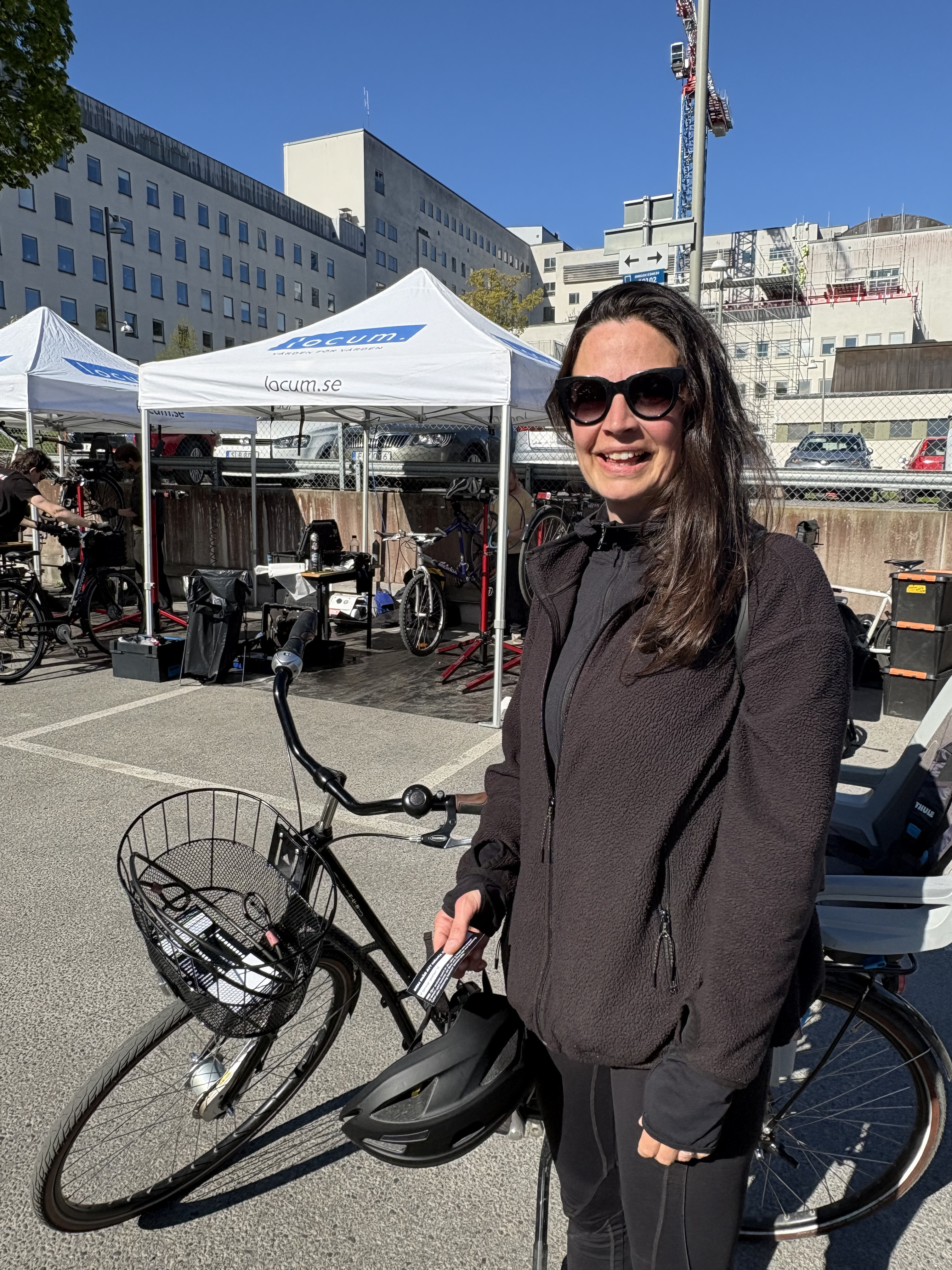 En kvinna i svarta kläder och solglasögon är på väg att lämna in sin cykel för service.
