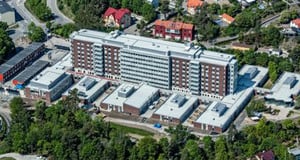 Flygfoto över Sollentuna sjukhus. Stor byggnad med en huskropp som består av både höghus- och låghusdel.