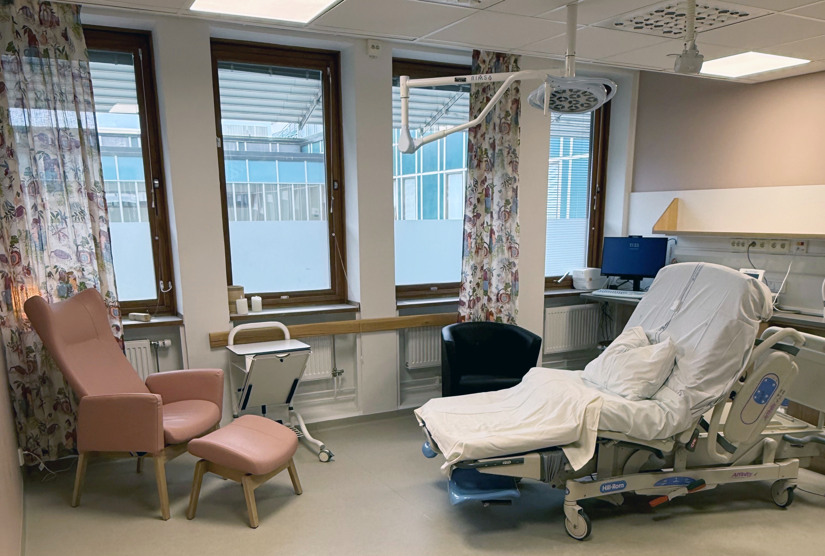 Inrett förlossningsrum med säng och fotölj.