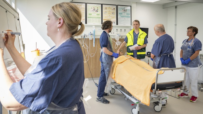 Vårdklädda människor i ett simuleringsrum.