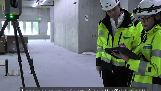 Albin Brette och Jenny Dolderer står vid en laserskanner inne på bygge.